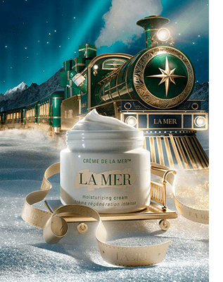 Crème de la Mer on a golden sledge in front of a green train travelling through a winter wonderland